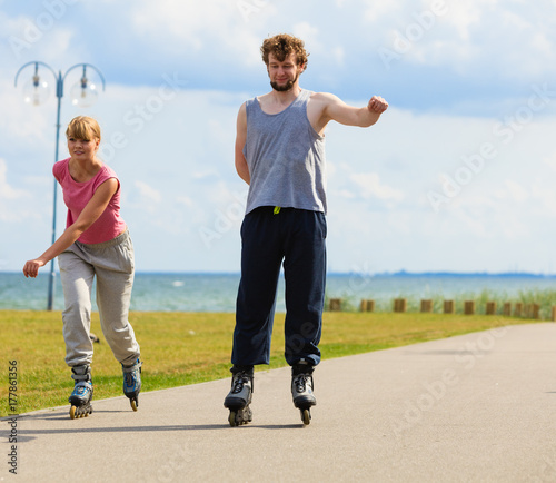 Young pair riding rollerblades in park.
