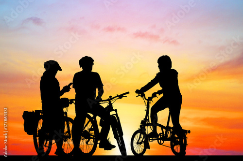 Groups of friends silhouette and bike on sunrise