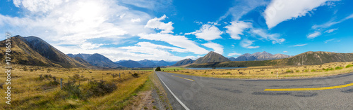 Rural Scene of Asphalt Road with Meadow and Mountain Range  South Island  New Zealand 