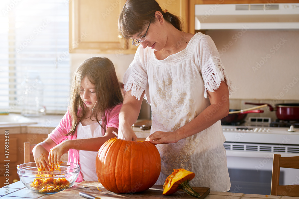 mother and daughter making jack-o-lantern from pumpkin for halloween ...