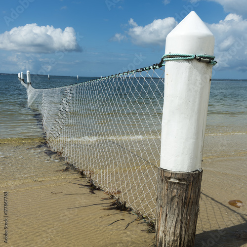 White corner post on shark net on beach pool. photo