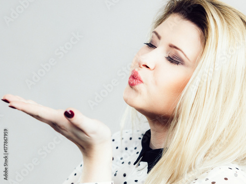 Coquet blonde woman sending air kiss
