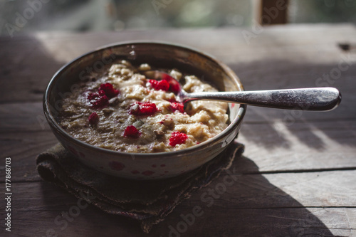 Porridge with raspberries in front of a window, cooling
