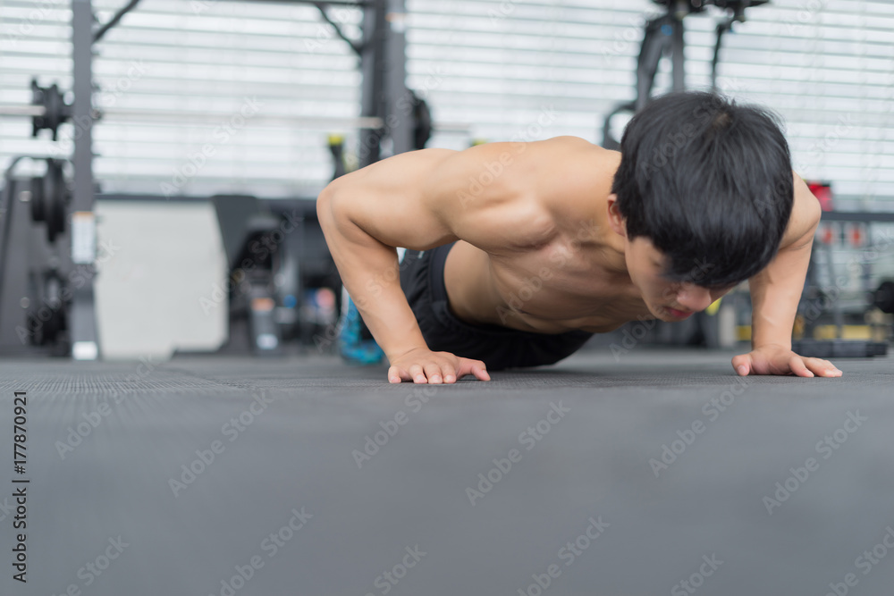 Fototapeta premium Fitness man showing push up exercises in gym