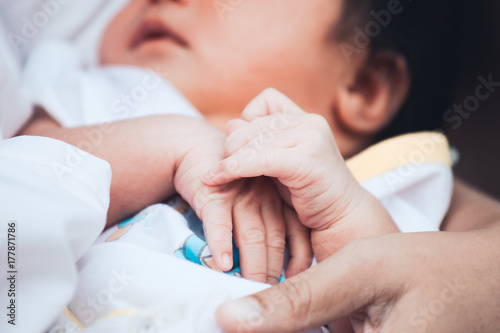 Newborn baby hands holding together while she sleeping on mother arm with tenderness