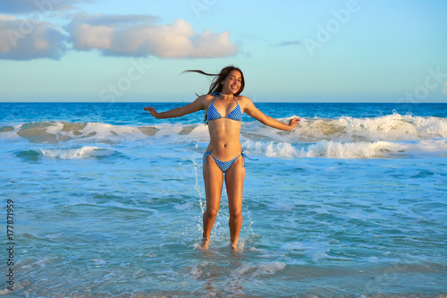 Latin bikini girl jumping in Caribbean beach