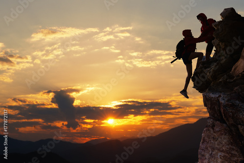 Teamwork hiking help each other trust assistance at mountains and beautiful sunrise,teamwork and hiking concept. photo