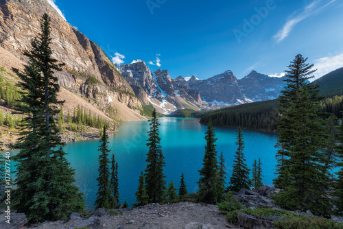 Beautiful turquoise waters of the Moraine Lake at sunset with snow-covered peaks above it in Rocky Mountains, Banff National Park, Canada.