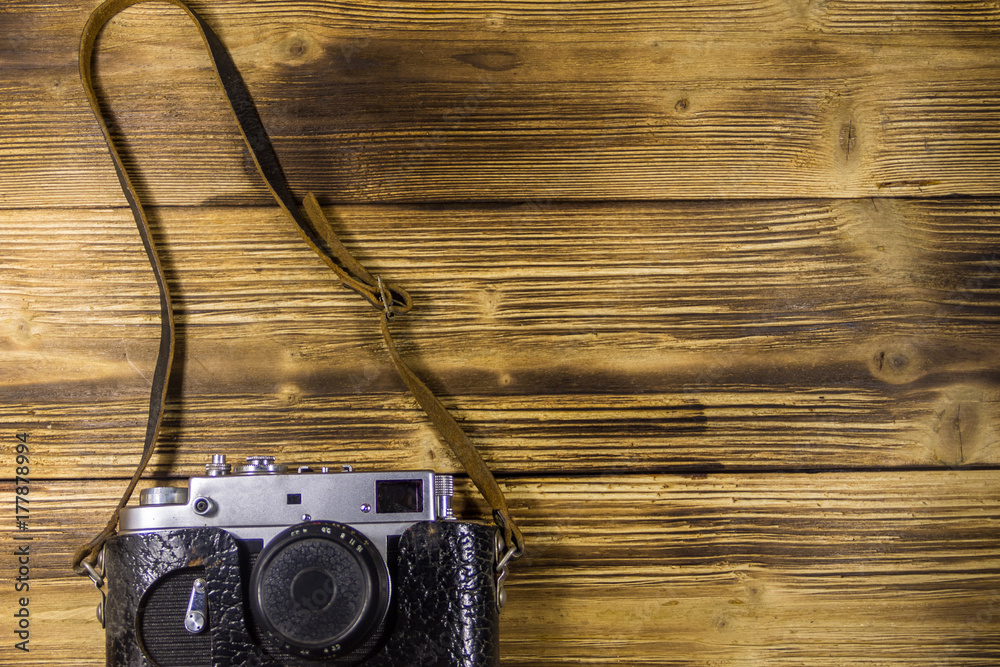 Retro photo camera in leather case on wooden background Retro photo camera in leather case on wooden background