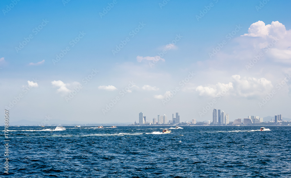 Speed boats and city buildings near the sea, sky and clouds