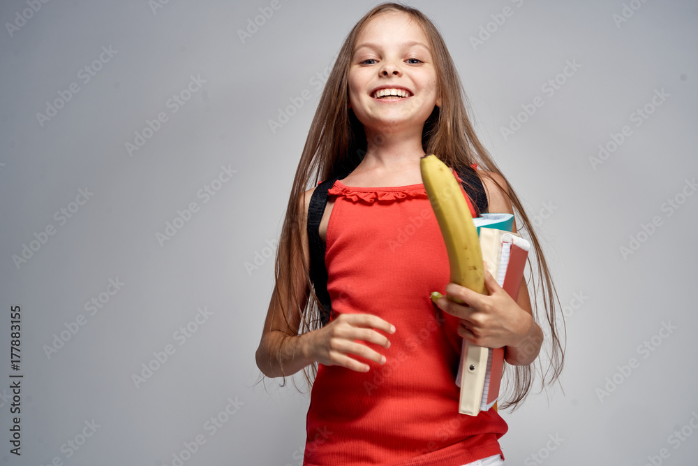 the girl laughs and holds a banana on a light gray background the girl laughs and holds a banana on a light gray background