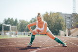 Female athlete does sport exercises in the stadium