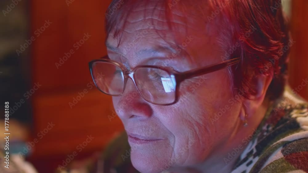 Face of elderly caucasian woman with glasses. Lenses reflect screen of computer monitor Face of elderly caucasian woman with glasses. Lenses reflect screen of computer monitor