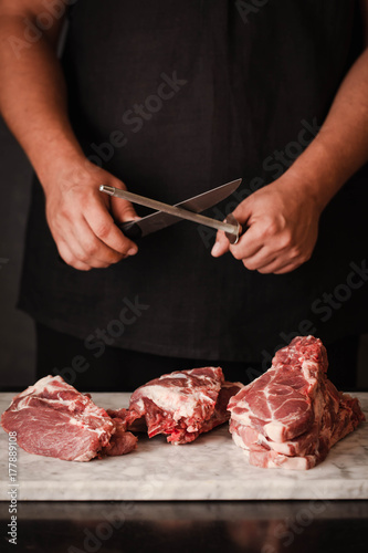 Person to grind knife and ready to cutting pork chops raw meat stack cooking grilling food 