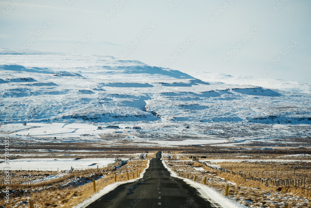 Empty country road in winter with snow capped mountain, focus on mountain