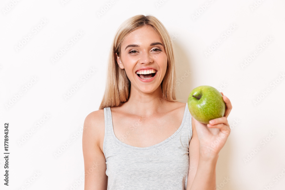 Portrait of a joyful girl in underwear showing green apple