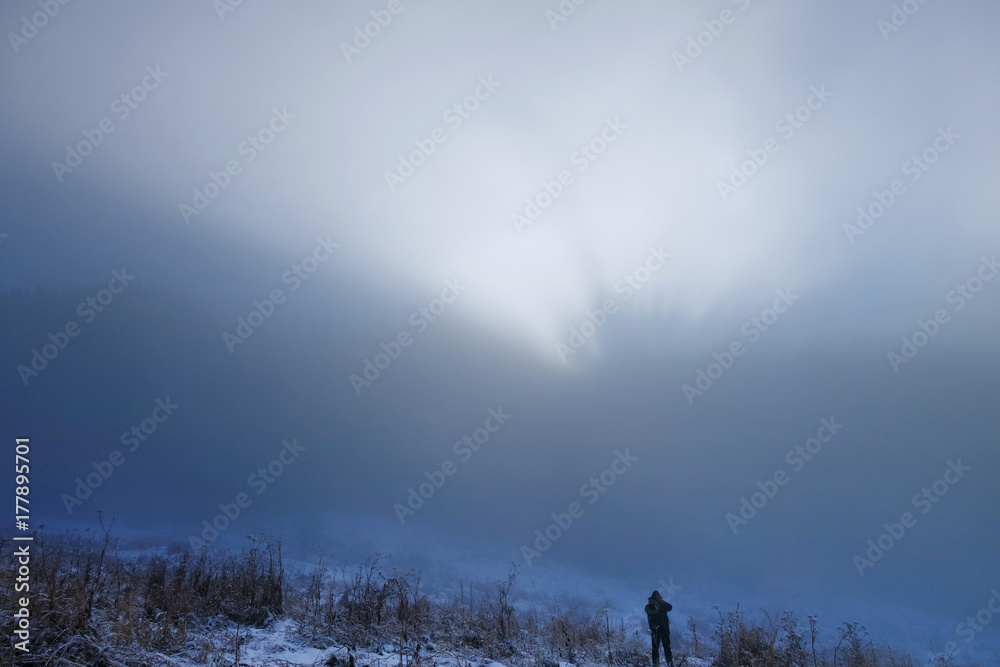 Man stands under huge low grey cloud in highlands of Zaili Alatau in Kazakhstan.