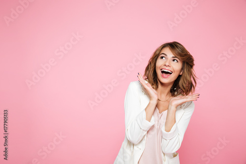 Smiling excited girl holding hands at her face