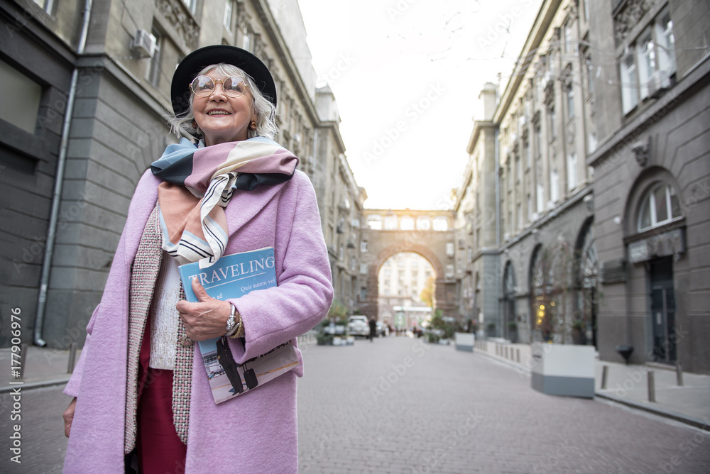 Excited senior lady standing with journal on street