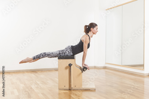 Beautiful woman performing pilates exercise  training on chair equipment