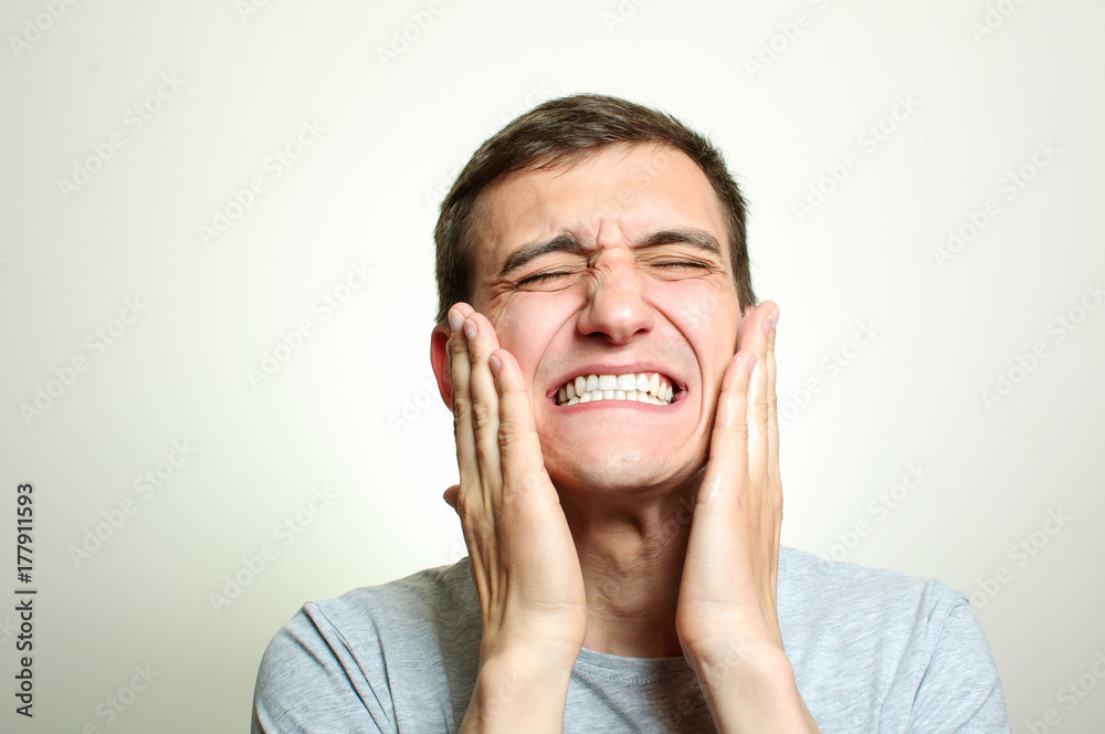 A young man after shaving smears the lotion with a pain expression A young man after shaving smears the lotion with a pain expression