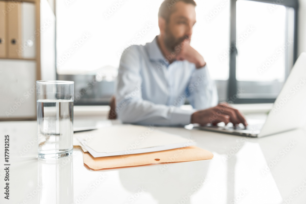 Thoughtful businessman typing on device Thoughtful businessman typing on device