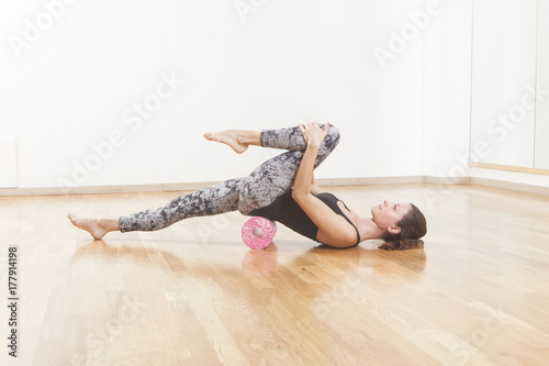 Beautiful woman pilates instructor stretching and warming up using foam roller
