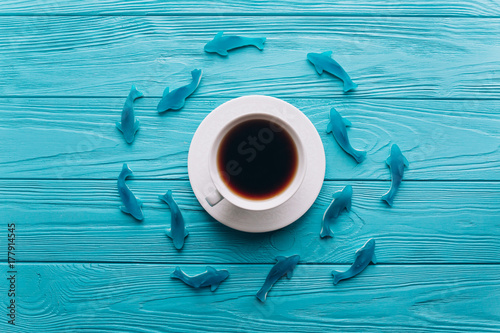 A cup of coffee on a wooden blue background with fish.