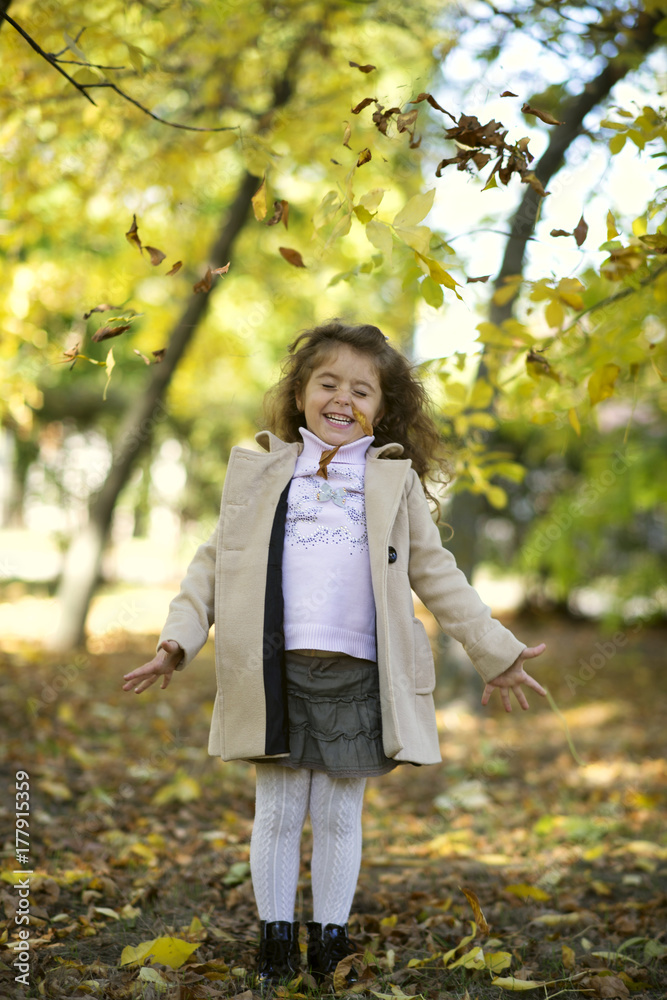 a curly-haired girl in an autumn park throws yellow leaves and laughs a curly-haired girl in an autumn park throws yellow leaves and laughs