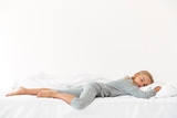 Full length portrait of sleeping peaceful girl in gray pajamas lying in bed