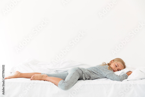 Full length portrait of sleeping peaceful girl in gray pajamas lying in bed © Drobot Dean