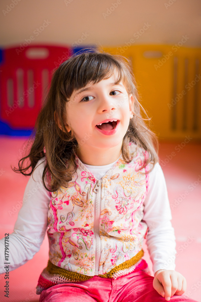 Portrait of little beautiful disabled girl who sitting on the mat indoor and smiling Portrait of little beautiful disabled girl who sitting on the mat indoor and smiling