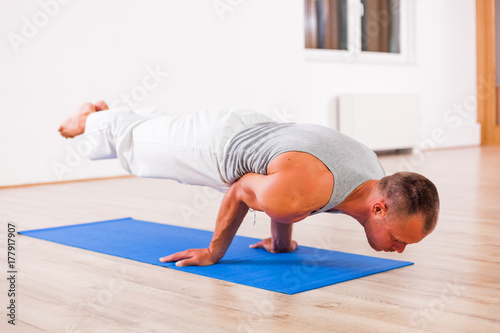 Adult man practicing yoga, Pincha Mayurasana / Feathered Peacock Pose