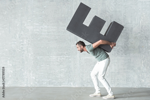 Cheerful cute guy is holding large symbol photo