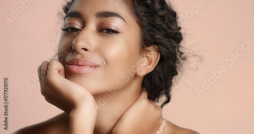 Close up video of a happy and relaxed young woman with perfect olive skin fixing her wavy black hair isolated on white