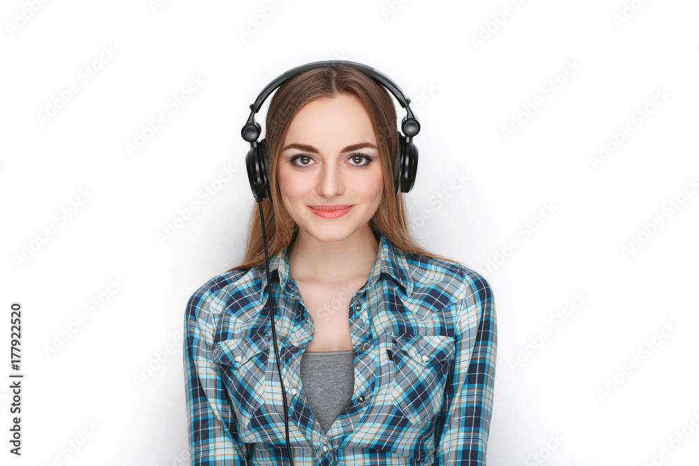 Headshot of a young adorable blonde woman in blue plaid shirt listening to big professional dj headphones. Headshot of a young adorable blonde woman in blue plaid shirt listening to big professional dj headphones.