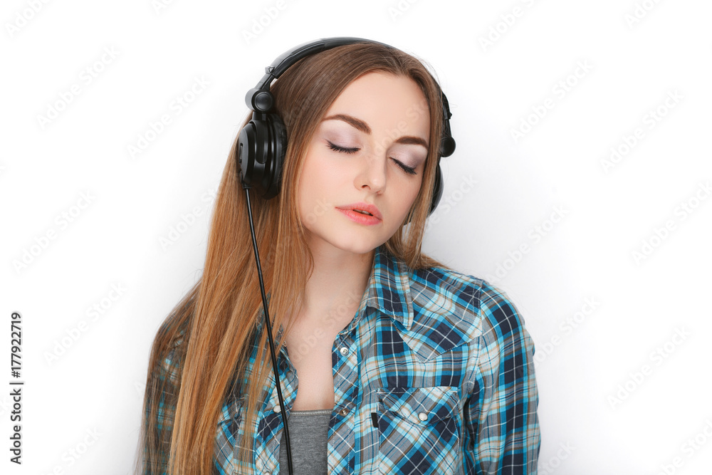 Headshot of a young adorable blonde woman in blue plaid shirt listening to big professional dj headphones. Headshot of a young adorable blonde woman in blue plaid shirt listening to big professional dj headphones.