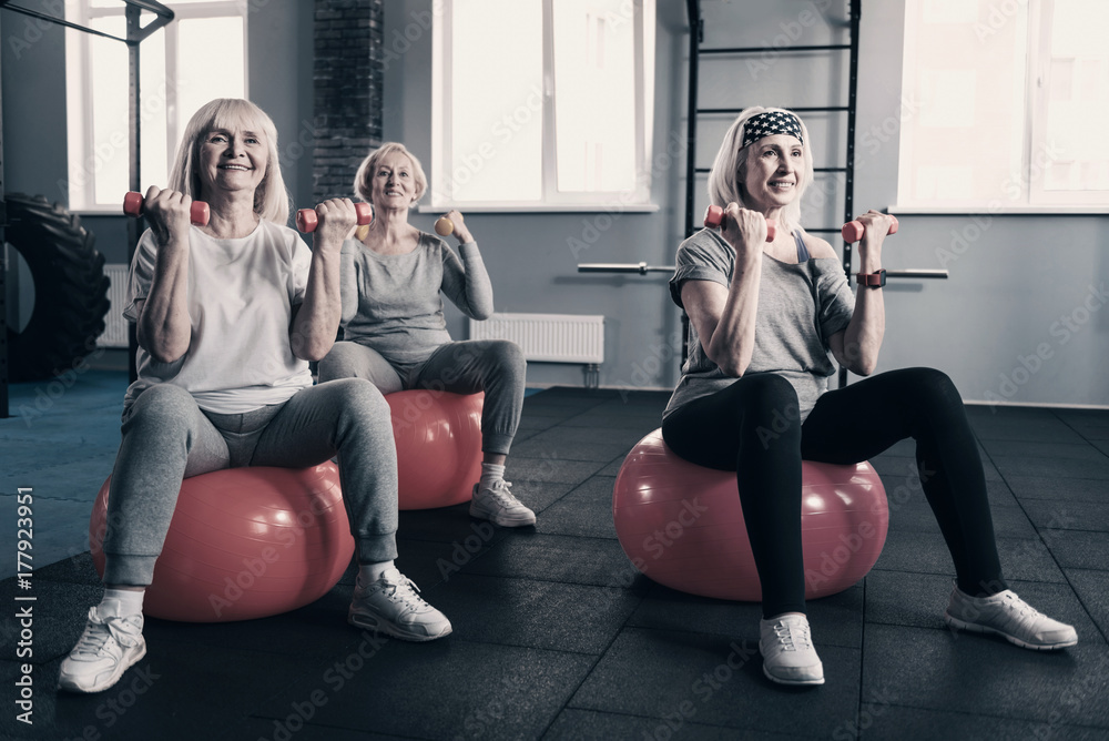 Obraz premium Elderly women working out with dumbbells on exercise balls