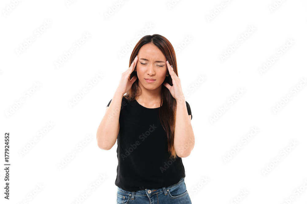 Young asian woman with closed eyes touching her head Young asian woman with closed eyes touching her head