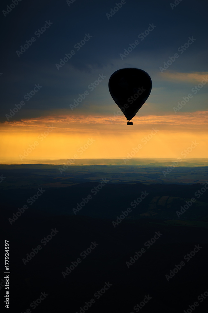 Fototapeta premium Aerial view of summer countryside during sunset with silhouette of hot air balloon