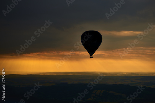 Aerial view of summer countryside during sunset with silhouette of hot air balloon