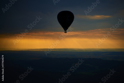 Aerial view of summer countryside during sunset with silhouette of hot air balloon