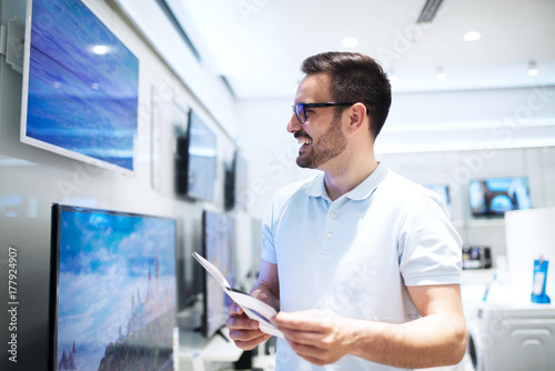Attractive bearded man looking for new tv in a tech store.