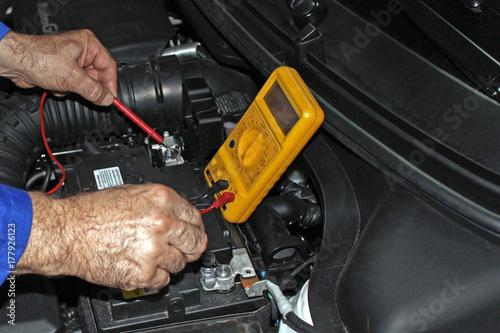 Mecánico comprobando el voltaje de la batería del coche