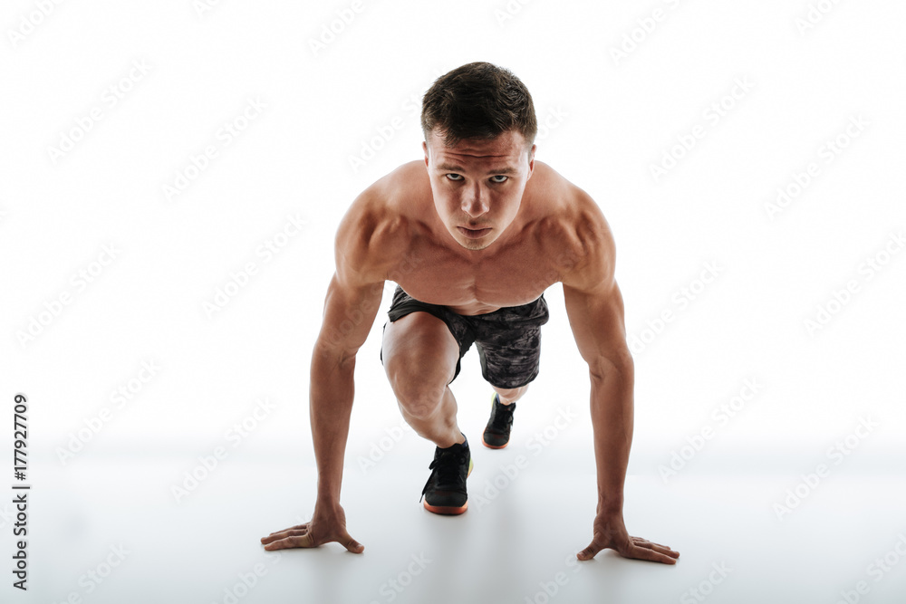 Φωτογραφία Close-up of young handsome runner with short haircut standing in start position,