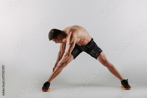 Concentrated young sportsman make stretching exercises