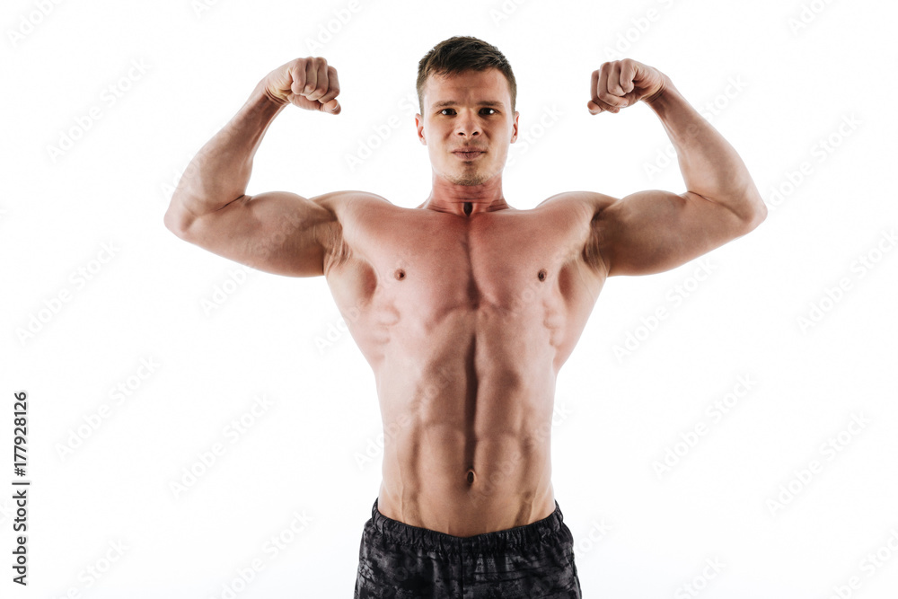 Close-up portrait of serious strong sports man showing his biceps, looking at camera