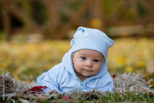 Newborn baby boy, curiously lifting his head, looking around in the park