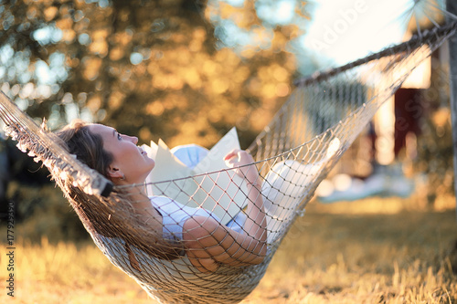 Beautiful girl in hammock reading a book 