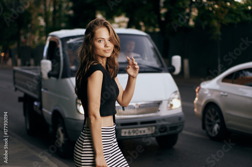 Friendly and beautiful girl on the street on the background of the car